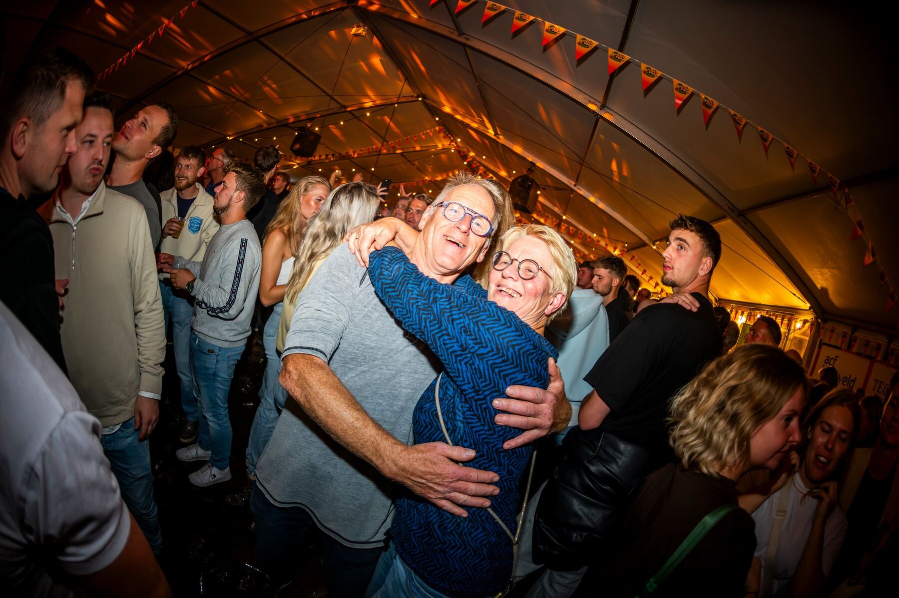 Twee bezoekers omarmen elkaar lachend